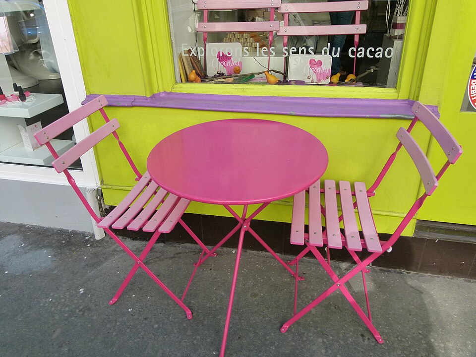 Table de bistrot et chaises sur un trottoir parisien